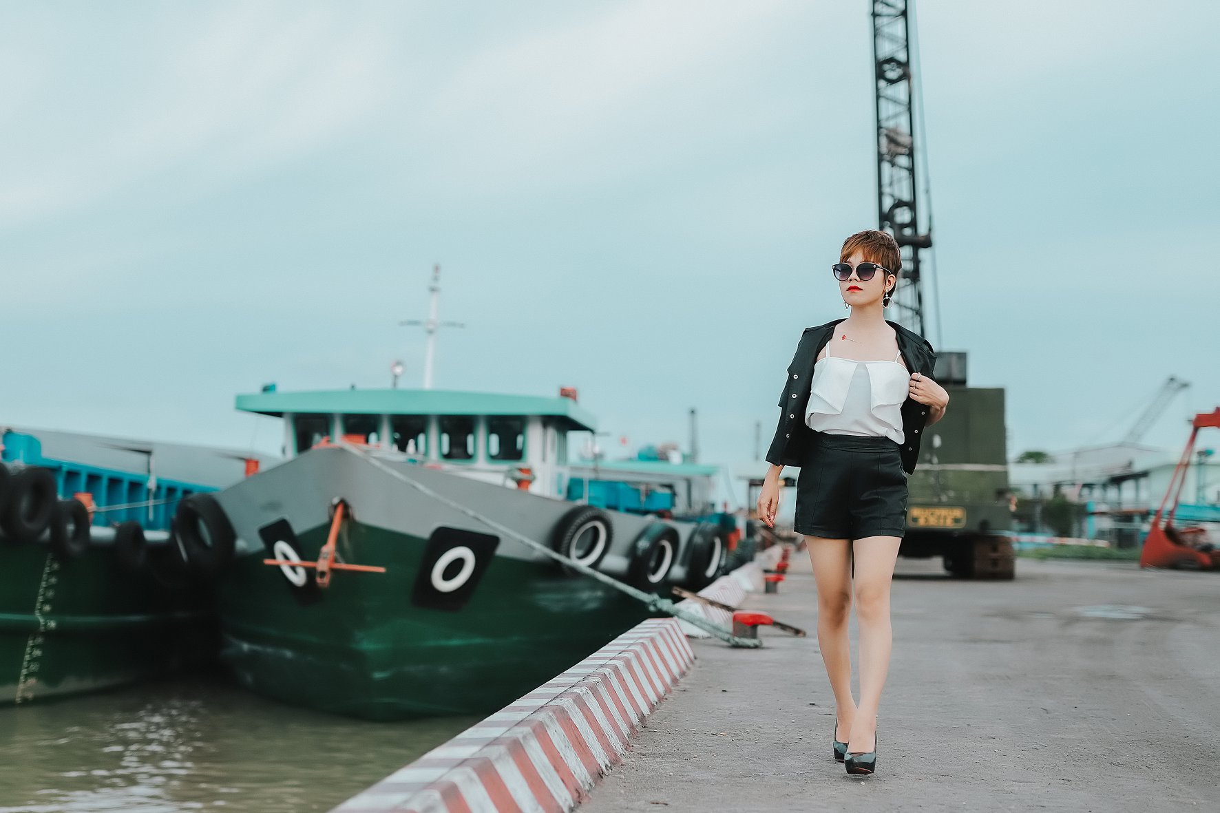 Phong cách urban chic: Tôn lên sự giao hòa giữa thanh lịch và mạnh mẽ với backdrop tàu thuyền xanh và nền bê tông sọc đỏ trắng đặc trưng